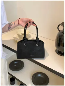 Schwarze Wildleder Handtasche Detailansicht mit geknoteten Griffen und Silberringen.