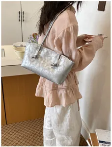 Detailed view of the stylish silver metallic shoulder bag with unique knot handle design.