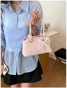 Detailansicht einer schicken hellrosa Handtasche mit eleganter Spitzen-Perlen-Schleife.
