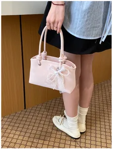 Nahaufnahme der rosa Handtasche mit weißer Schleife und Perlen, süßes Detail und Design.