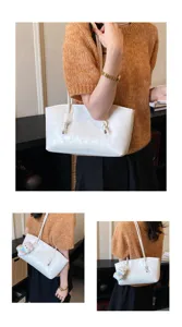 Detailed view of white minimalist shoulder tote bag with knot detail and plush charm.