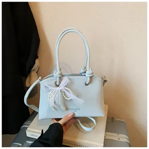 Detailansicht der hellblauen PU-Leder-Umhängetasche, eleganter Perlen-Spitzen-Anhänger und Knotengriff.