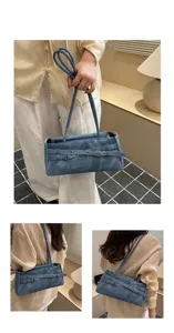Denim underarm bag detail showing stylish belt decoration and long straps for chic look.