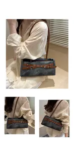 Detailed view of grey denim shoulder bag with brown buckle straps worn by model indoors.