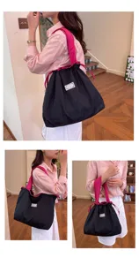 Gedetailleerd overzicht van de zwarte casual schoudertas met roze contrasterende koorden.