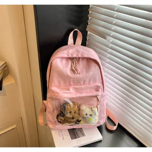 Close-up detail of a pink polka dot backpack featuring a clear front pocket and cute plush toys.