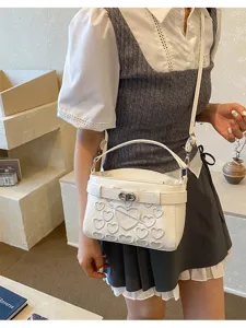 White leather crossbody shoulder bag featuring embossed hearts and a sleek metal buckle lock detail.