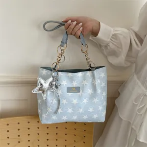 Detail van de blauwe shopper tas met sterrenprint, metalen kettinghengsels en zilveren sterhanger.