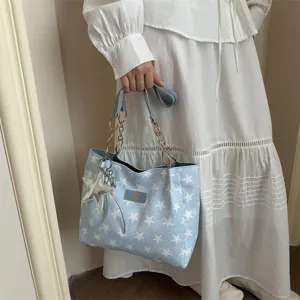Detailweergave van blauwe tote bag met sterprint, gouden ketting en sterrenhanger.