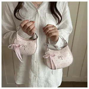 Vista detallada del mini bolso hobo rosa de lunares con un lindo lazo y colgante de perlas.
