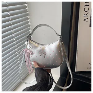 Primer plano del bolso plateado de lunares con lazo bonito y detalle de cinta de perlas.