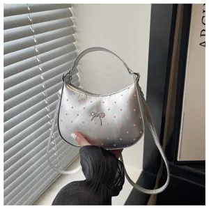 Primer plano de bolso plateado de hombro con lunares rosas y bonito detalle de lazo.
