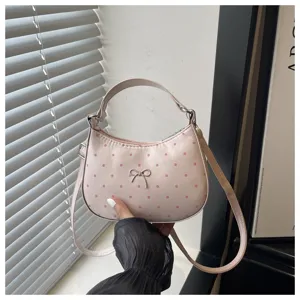 Bolso de mano de media luna con lunares rosas y lazo, detalle de bolso bandolera mujer.