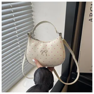 Vista detallada del bolso de mano de media luna con lunares y lazo, accesorio de moda.