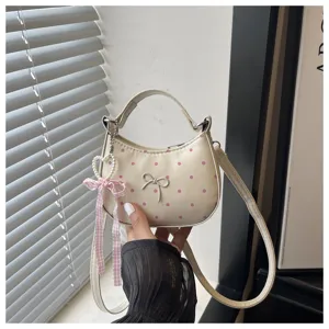 Detalle de bolso de mano de lunares con lazo y colgante de corazón de perlas muy bonito.