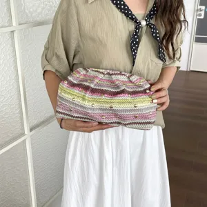 Gros plan sur la pochette tissée colorée avec des clous métalliques élégants et rayés.