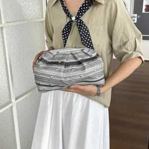 Gros plan d'une pochette tissée avec des rivets métalliques, élégant design gris et noir.