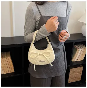 Detail view of stylish beige hobo bag featuring rhinestone stars and an elegant bow accent.