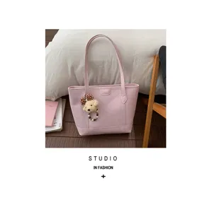 Pink tote bag detail view, showcasing large capacity, smooth leather texture and cute bear charm.
