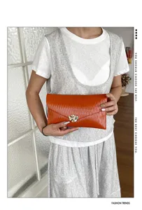 Stylish orange leather envelope clutch bag for women, perfect for commuting and party events.