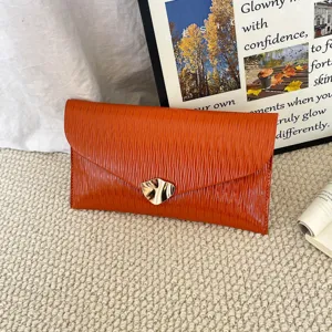 Orange textured envelope clutch bag featuring a sleek abstract gold metal clasp detail.