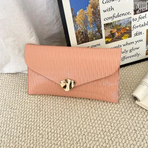 Detailed view of chic peach pink envelope clutch bag with unique gold metallic clasp texture.