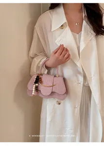 Bolso de mano rosa con solapa ondulada detalle con abalorio de madera y toque metálico.