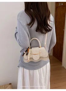 Primer plano del detalle del bolso cruzado de diseño de nicho elegante con su forma ondulada única.