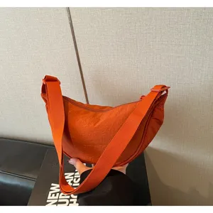 Primo piano della borsa a tracolla a mezzaluna in nylon arancione, tessuto resistente.
