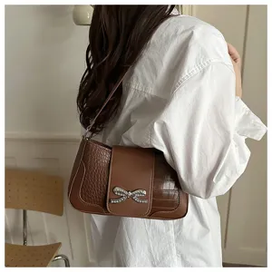 Bolso de hombro marrón con efecto cocodrilo y detalle de lazo de pedrería brillante