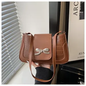 Bolso de hombro marrón con textura de cocodrilo y lazo de diamantes de imitación brillante.