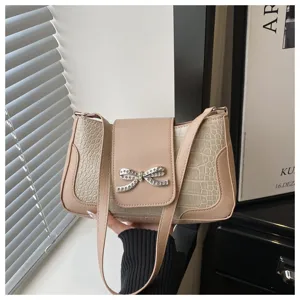 Vista detallada del elegante bolso de hombro beige con brillante lazo de pedrería.