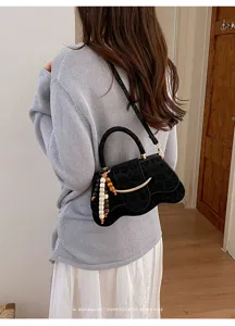 Detalle de un bolso de hombro con estampado de leopardo y diseño ondulado con cuentas.