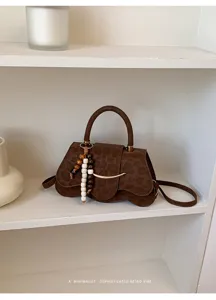 Vista detallada del bolso retro de leopardo con barra de metal y abalorio de cuentas de madera.