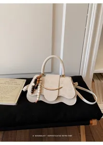 Bolso bandolera retro minimalista con barra de sonrisa metálica y cuentas de madera.