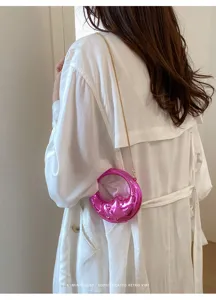 Detailansicht der glänzenden rosa Halbmond-Minitasche mit goldener Kette am Model.