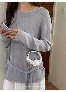 Detailaufnahme der silbernen runden Mini Tasche kombiniert mit einem grauem modischen Top.