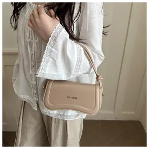 Detailed view of the chic beige leather underarm shoulder bag with a unique curved bottom design.