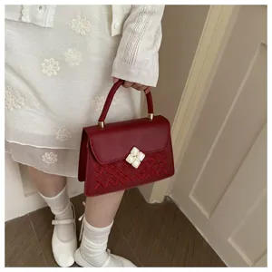 Nahaufnahme einer dunkelroten bestickten kleinen Handtasche mit Kleeblatt-Verschluss.
