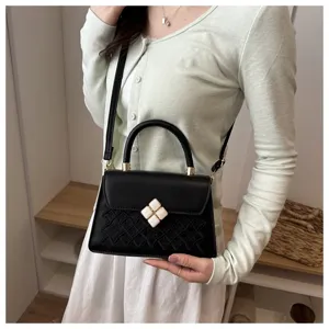 Schwarze elegante kleine quadratische Handtasche mit geprägtem Gittermuster und Schulterriemen.