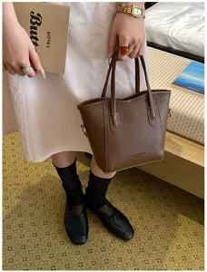 Detailed view of brown leather bucket bag, chic handbag with shoulder strap for daily wear.