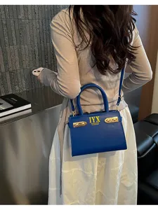 Stylish blue textured handbag detail, elegant top handle and shoulder strap design.