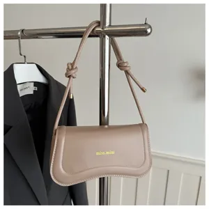 Chic beige shoulder bag for women, stylish faux leather crescent baguette bag with knot strap.