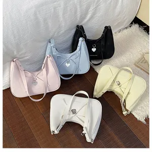 Vue détaillée de sacs à épaule tendance avec nœud et pendentif cœur sur sol en bois.