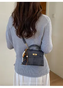 Vue détaillée d'un sac à main bandoulière de style rétro en gris foncé avec fermoir.