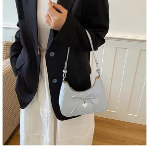 Gros plan détaillé du sac à épaule bleu clair avec joli nœud et pendentif cœur.