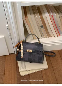 Vue detaillee du sac a main texture retro avec fermeture a tourillon et perles en bois.
