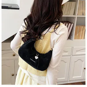 Vue détaillée du sac à bandoulière en suédine noire avec nœud et pendentif cœur.