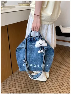 Close-up detail of the denim canvas shoulder bag showing letter prints and cute cloud charm.