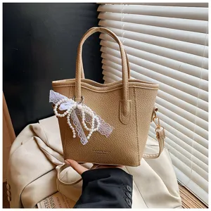 Beige leather bucket bag with pearl lace bow pendant, stylish commuter handbag for women.
